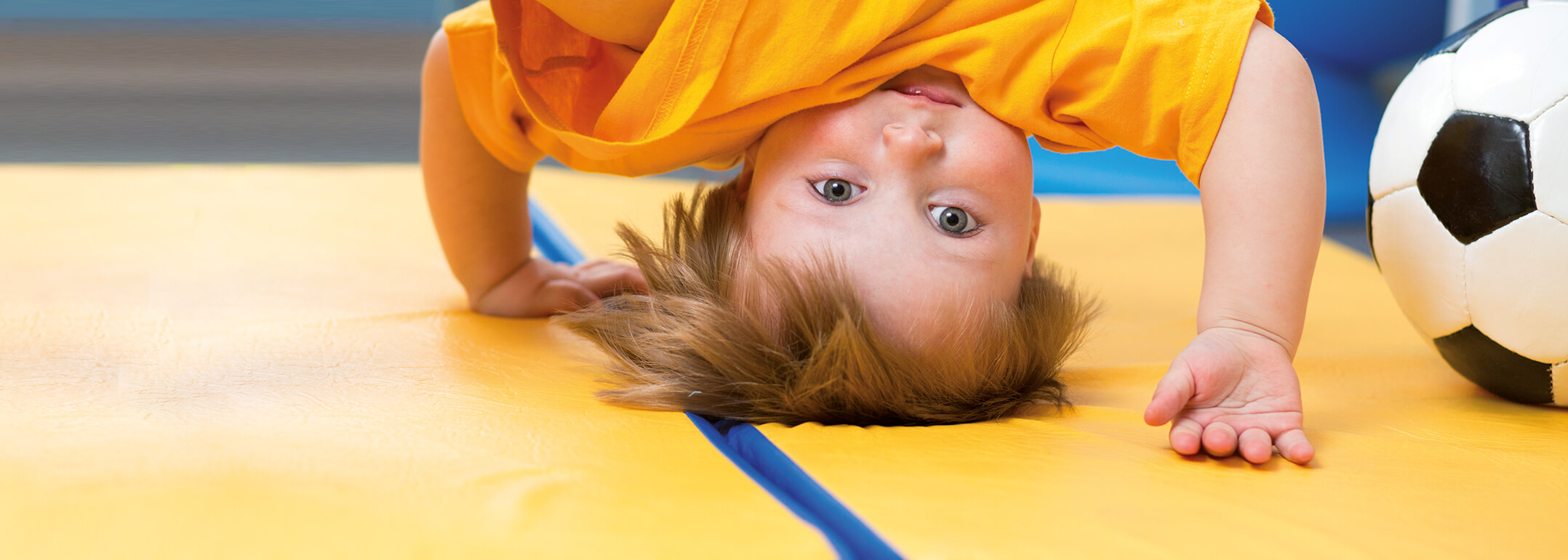 Ein Kleinkind macht Kopfstand auf einer Turnmatte