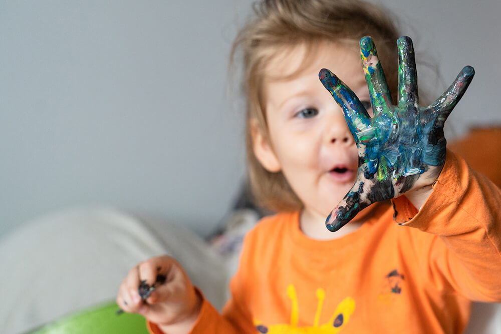 Ein Kleinkind malt mit Fingerfarben